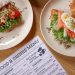 Top view of delicious salmon croissant and sandwich with fresh ingredients on wooden table.